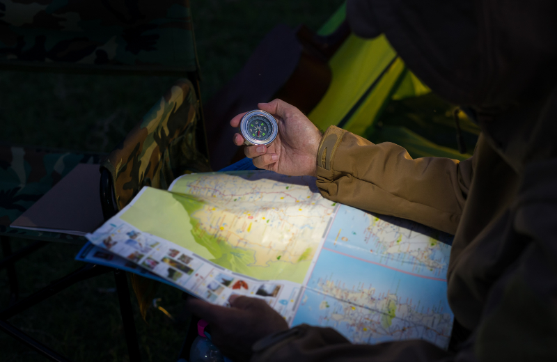 Man met kaart, kompas en zaklamp in het bos tijdens een dropping. - Oxtarn Clinics & Adventures