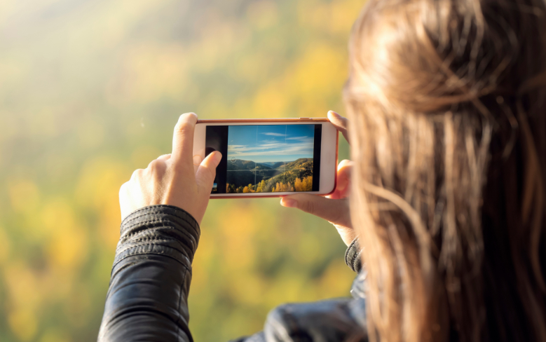 Vrouw met iphone tijdens een clinic smartphone natuur fotografie in het bos van Castricum. - Oxtarn Clinics & Adventures