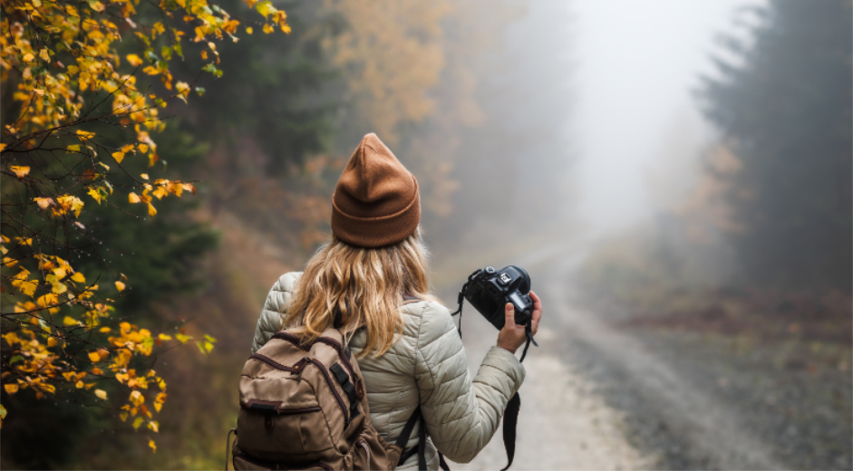 Vrouw in het bos van Castricum, lopend over een pad met ee spiegelreflex camera. - Oxtarn Clinics & Adventures