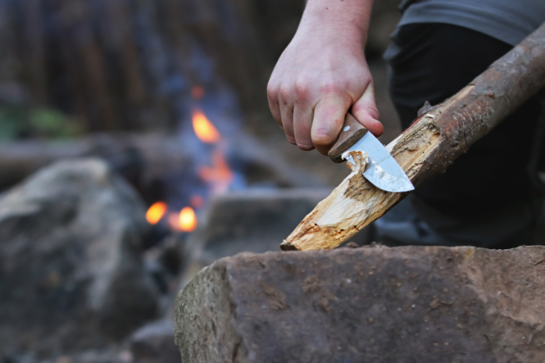 Man bezig met het snijden van een stok tijdens de Survival Clinics. Man bezig met het snijden van een stok tijdens een Survival Clinic. - Oxtarn Clinics & Adventures